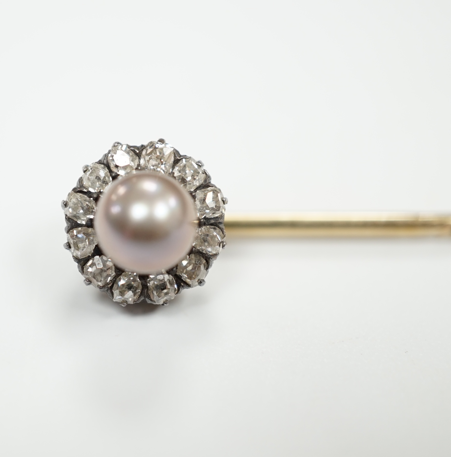 An early 20th century yellow metal, cultured pearl and old cut diamond cluster set stick pin, 70mm, gross weight 2.8 grams.